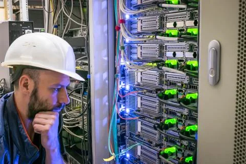 The engineer thinks how to properly connect the wires in the data center serv 库存照片