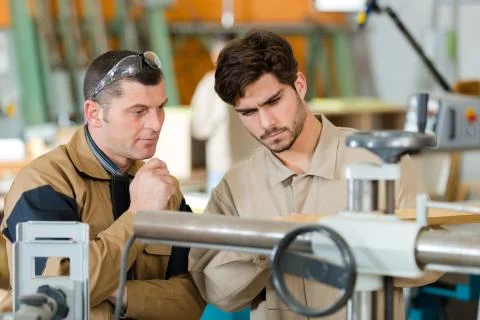 Engineer training apprentices on machine Stock Photos