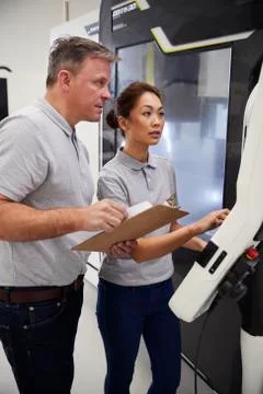 Engineer Training Female Apprentice To Use CNC Machine In Factory Stock Photos