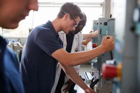 Engineer training male apprentice using a drill press 스톡 사진