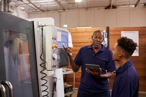 Engineer Training Young Male Apprentice On CNC Machine Stock Photos