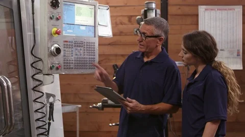 Engineer Trains Female Apprentice On CNC Machine Shot  Stock Footage 72512422