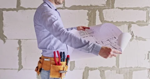 Engineer unfolds floor plan assessing upcoming work scope 動画素材 309080685