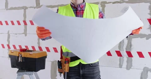 Engineer unfolds rolled floor plan and examines apartment layout Video stock 309923386