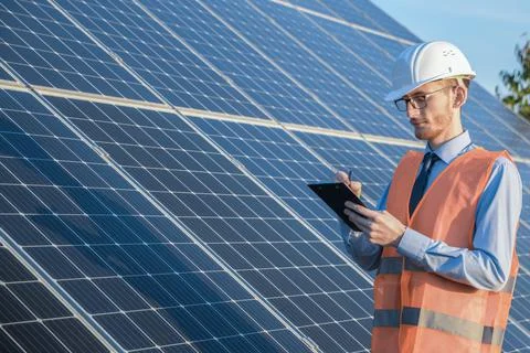 Engineer in uniform standing on a background of solar panels.The solar farm c Stock Photos