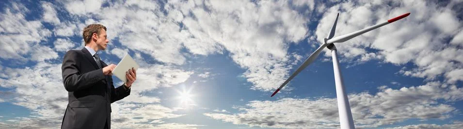 Engineer use the tablet, background wind turbine and blue sky with sun Stock-Fotos