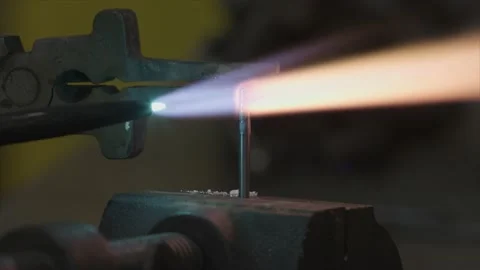 Engineer Uses Blow Torch to fuse two tiny pieces of metal together, fire glowing Video stock 136800064