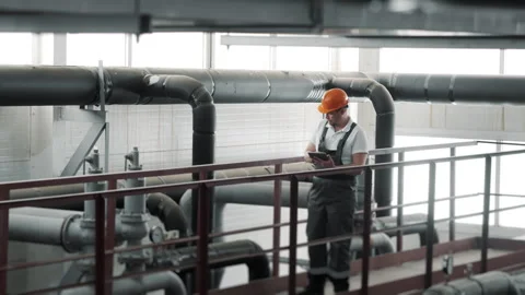 An engineer uses a computer tablet to inspect pipe connection at the factory. Stock Footage 306816347
