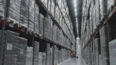 The engineer uses a forklift to remove pallets with goods from the shelves. Stock Footage 276643537