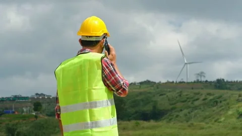 Engineer uses a smartphone to discuss wind turbine teamwork techniques Stock Footage 143002646