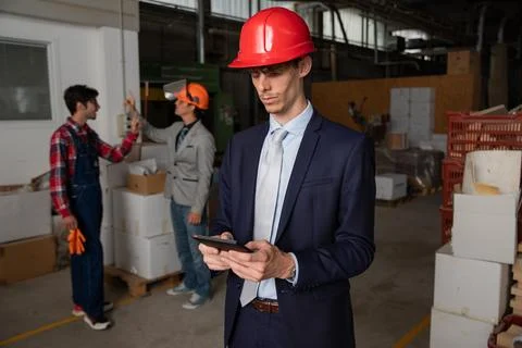 An engineer uses a tablet on the construction site while wearing a hard hat.. Stock Photos