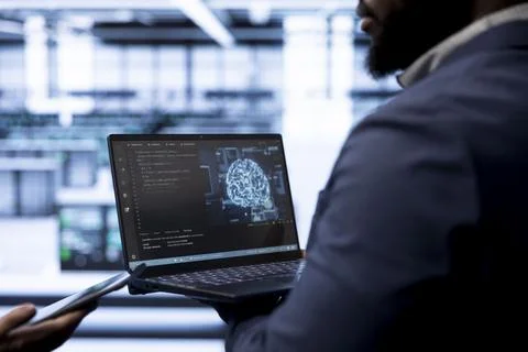 Engineer using AI software on laptop, programming in data center Foto stock