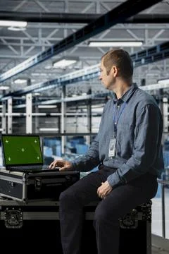 Engineer using chroma key laptop in server hub, conducting installations Foto stock