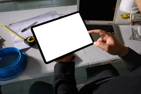 Engineer using digital tablet at construction planning desk with tools and Stock Photos