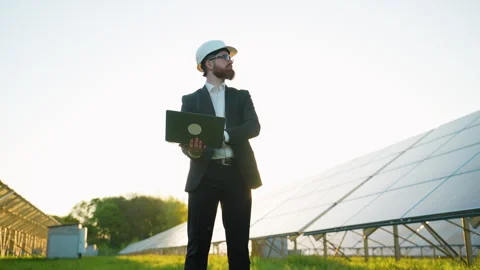 Engineer using laptop analyzing solar panels in sunlight Stock Footage 314408713