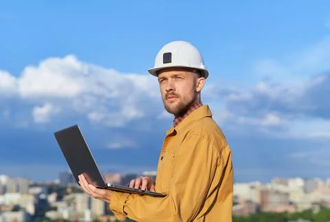 Engineer using laptop at construction site with urban skyline Stock Photos
