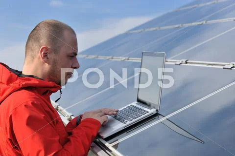 Engineer using laptop at solar panels plant field Stock Photos