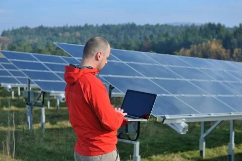 Engineer using laptop at solar panels plant field Stock Photos