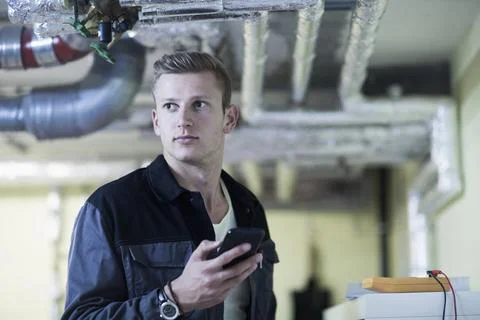 Engineer using mobile phone in workshop, Freiburg Im Breisgau, Baden-württemberg Stock Photos