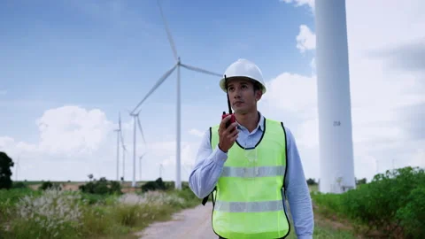 Engineer using a radio to deliver work orders while inspecting a wind farm Stock Footage 165444038