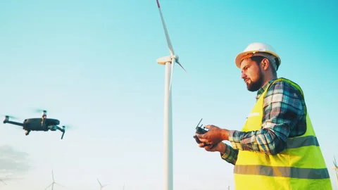 Engineer using a remote control controls a drone to inspect a wind park Stock Footage 247845753