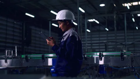 Engineer is using a tablet to check the machine's control system in a factory. Stock Footage 165870970