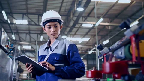 Engineer is using a tablet to check the machine's control system in a factory. Stock Footage 165871975