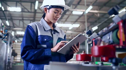 Engineer is using a tablet to check the machine's control system in a factory. Stock Footage 165872090