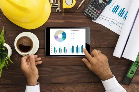 Engineer using tablet checking business graph on work table Stock Photos