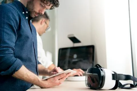 Engineer using tablet computer while colleague using computer in office Stock Photos