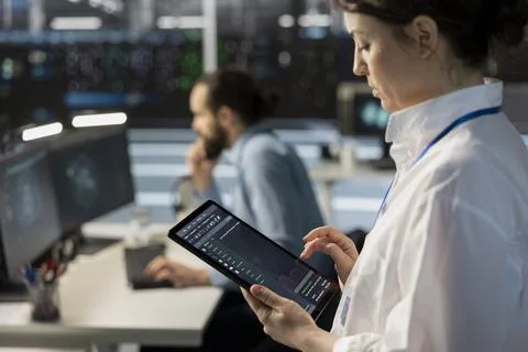 Engineer using tablet in data center, managing servers, running scripts, closeup Stock Photos