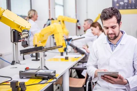 Engineer using tablet in factory with industrial robots 스톡 사진