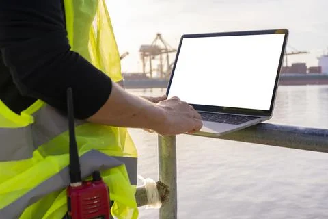 An engineer is using a tablet to work, she is at the shipping dock. Use radio Stock Photos