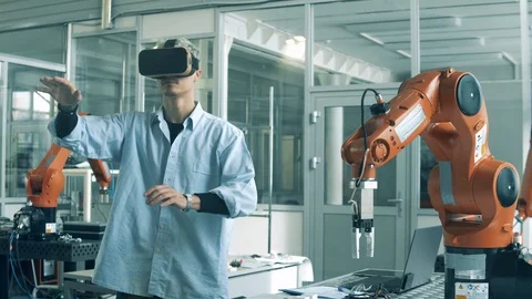 Engineer in VR-glasses is manipulating a bionic device. High school students Stock Footage 128418058