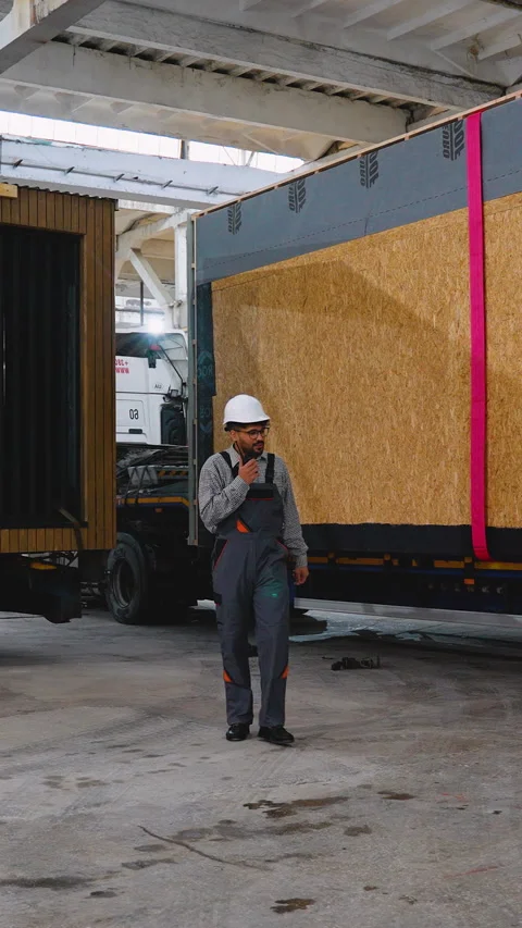 Engineer walking and talking on walkie talkie in warehouse with prefabricated Stock Footage 313091832