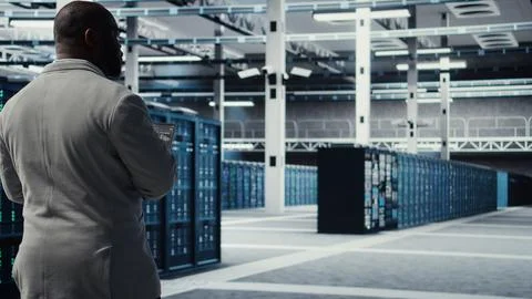 Engineer walking in data center using device to configure hardware Stock Photos