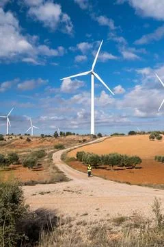 Engineer walking on a dirt road inspecting wind turbines in countryside Stock Photos