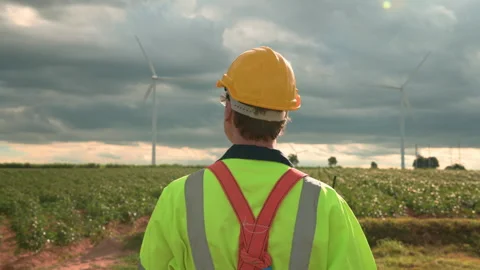 Engineer is walking in a field wearing a protective helmet on  head Stock Footage 269098991
