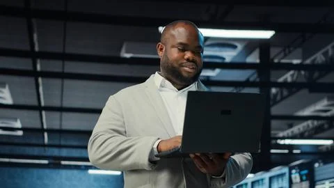 Engineer walking in server room backing up storage arrays using software Stock Photos