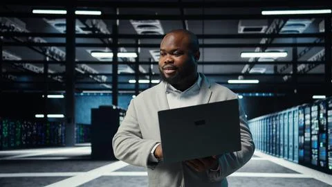 Engineer walking in server room backing up storage arrays using software Stock Photos