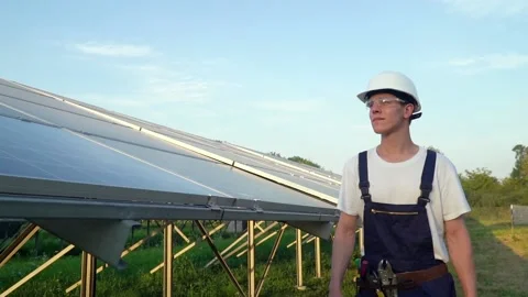 Engineer walking in solar cell farm through field of solar panels checking the Stock Footage 137266082