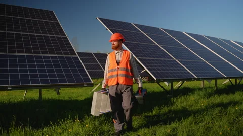 Engineer walking in solar panel farm carrying equipment Stock Footage 314405384