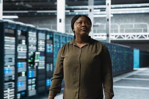 Engineer walking through server farm rows lined with storage infrastructure Stock Photos