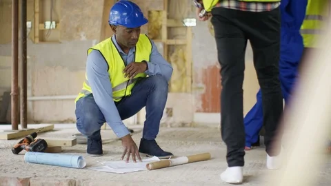 Engineer watching blueprint and looking g around at construction site Stock Footage 108170160