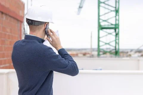 Engineer wearing a hard hat. Standing outdoors at a busy construction site... Stock Photos