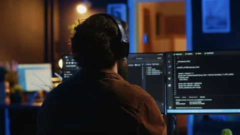 Engineer wearing headphones while using coding to fortify IT security Stock Footage 265510956