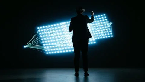 Engineer wearing VR headset gear to look at glowing AI neural network Stock Photos
