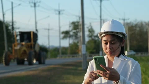 Engineer wearing a white helmet using a smartphone in a workplace. Stock Footage 229705295