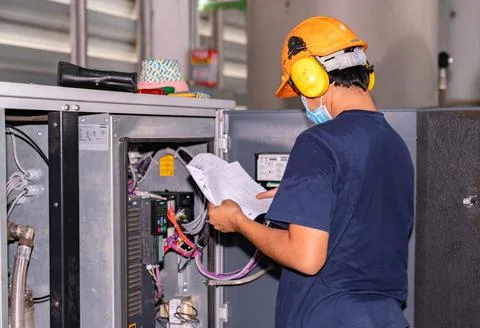 The engineer wears an ear muff while checking the air compressor. Stock Photos