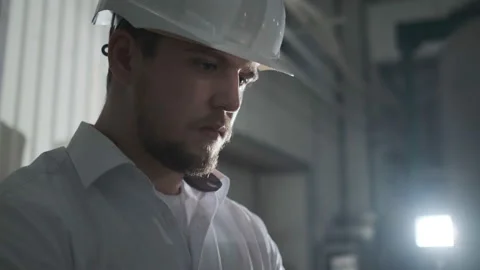 Engineer in white helmet and white clothes includes the machine in the factory Stock Footage 107412559